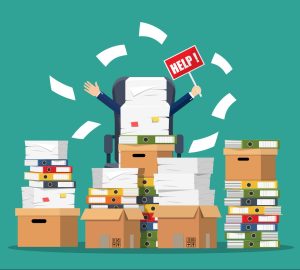 a person sitting in a chair surrounded by stacks of papers