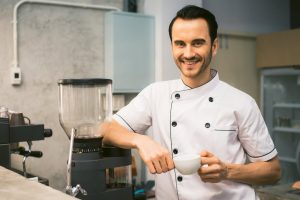 a man in a chef uniform holding a cup